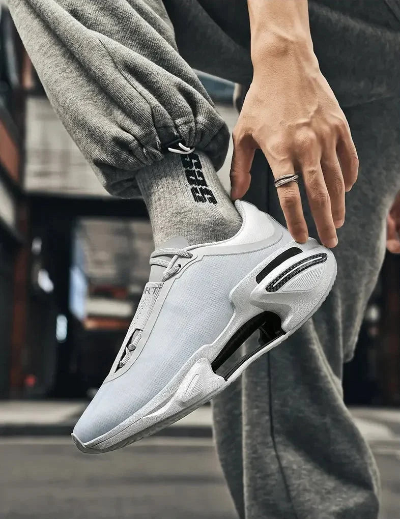 White athletic shoe with black accents worn by a person in gray pants.